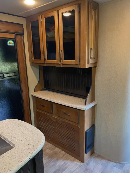 This RV rental features a well-appointed kitchen area with light wood cabinetry, a speckled countertop, and a built-in refrigerator.. Reflection BHT33 2018