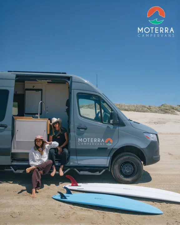 Enjoy the freedom of an RV rental! Two women relax with surfboards by their Moterra campervan on a sunny beach.. Mercedes-Benz Sprinter 2021