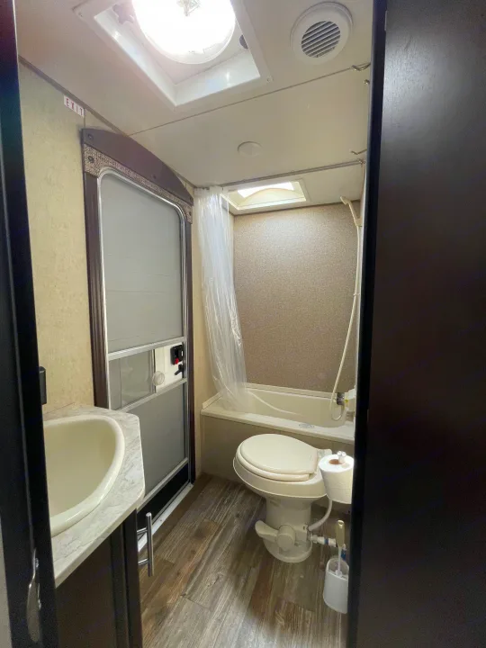 Clean RV rental bathroom showcasing a vanity sink, toilet, and full tub/shower. A bright interior for your travels.. Forest River Cherokee Grey Wolf 2017