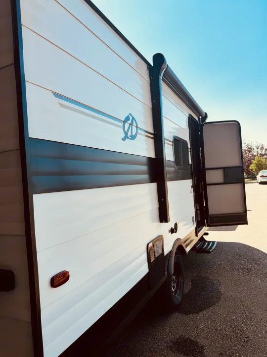 Side view of a white and black travel trailer, a perfect RV rental for your next outdoor adventure.. Cruiser RV Avenir 2024