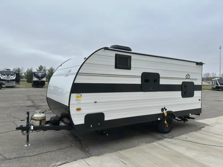 A white and black travel trailer with a front propane tank is parked on asphalt, ideal for an RV rental adventure.. Cruiser RV Avenir 2024