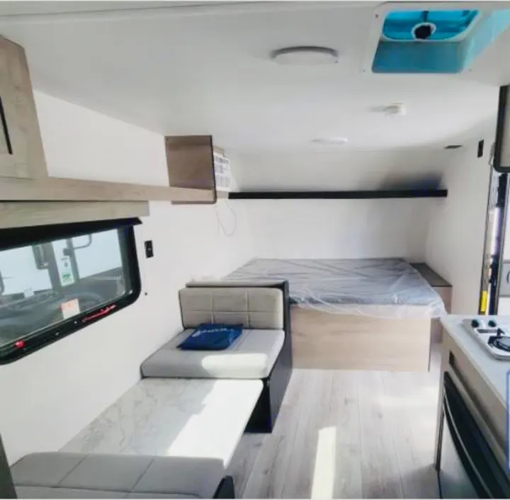 This RV rental interior features a bed, convertible seating, overhead storage, and a kitchenette, perfect for travel.. Cruiser RV Avenir 2024