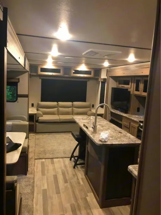 Spacious rv rental interior featuring a kitchen island, sofa, and dining booth. Perfect for comfortable journeys.. Crossroads RV Zinger 2020
