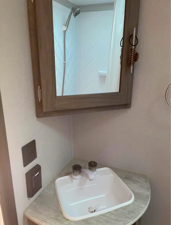 RV rental's compact bath features a corner sink, mirror reflecting the shower, and wall outlets.. Crossroads RV Zinger 2020