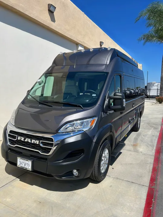Dark gray Ram ProMaster van ready for your next rv rental. Parked curbside, perfect for road trips.. Thor Tellaro 2024
