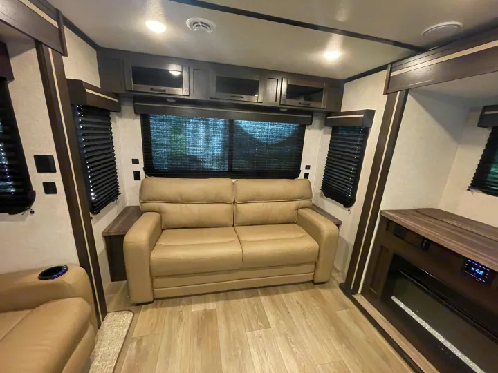 Modern RV rental living space featuring a comfortable sofa, ample cabinetry, and an electric fireplace.. Crossroads RV Cruiser Aire 2022