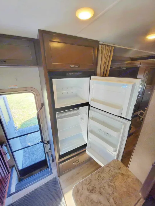 RV rental: Inside view of an open, empty refrigerator, overhead cabinets, and entry steps to the outside.. Thor Four Winds 2020