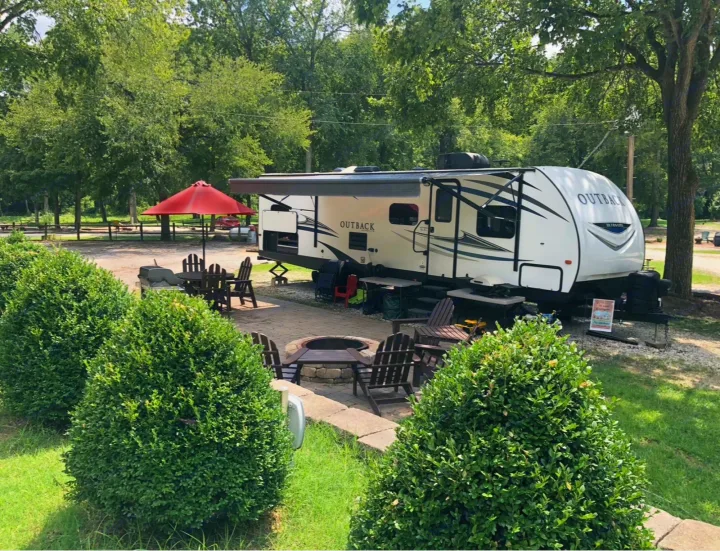 Relaxing RV rental setup: an Outback RV with awning, fire pit, and chairs at a scenic campsite.. Keystone RV Outback Ultra-Lite 2018