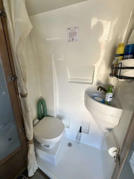 Interior of an RV rental's compact white wet bath featuring a toilet, sink, and shower curtain.. Forest River Coachmen Crossfit 2018
