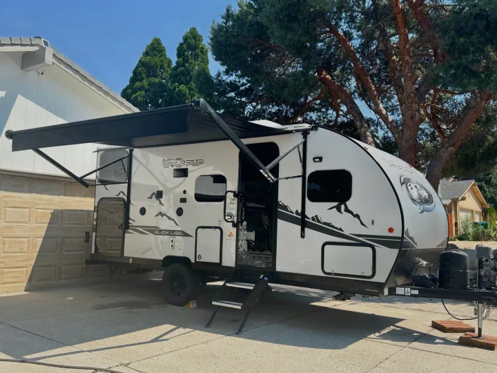 White Wolf Pup RV with extended awning & steps, parked in a driveway. Perfect for an RV rental adventure.. Forest River Cherokee Wolf Pup Black Label 2022