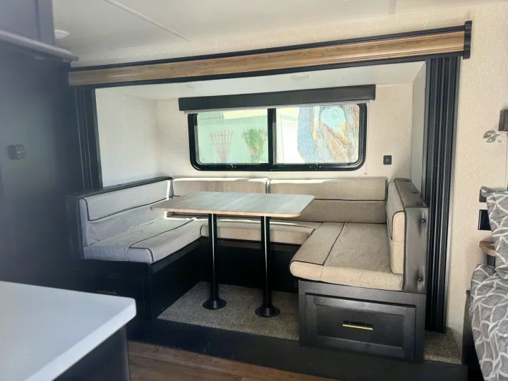 Spacious U-shaped dinette with light cushions, table, & window in this rv rental. Perfect for your travel trailer or camper.. Forest River Cherokee Wolf Pup Black Label 2022