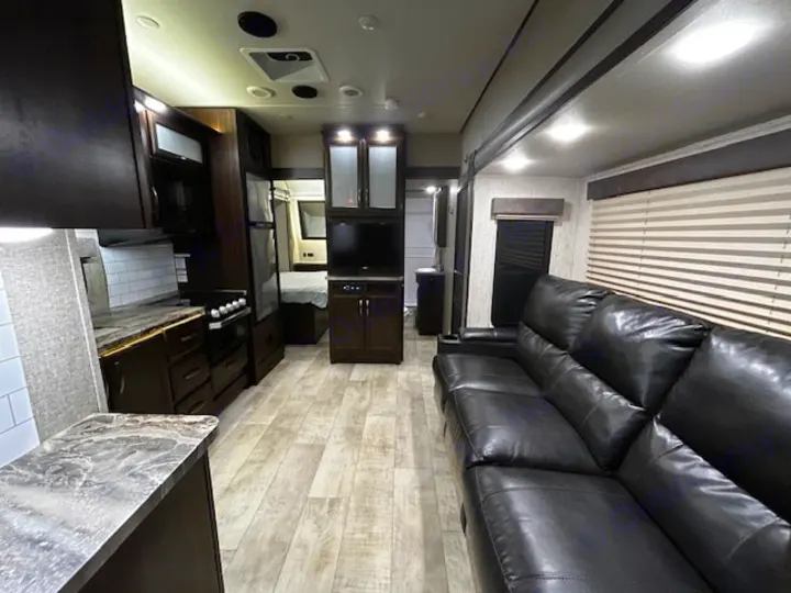 Step inside this sleek rv rental, showcasing its modern kitchen, living room with sofa, and cozy bedroom.. Grand Design Momentum 2020
