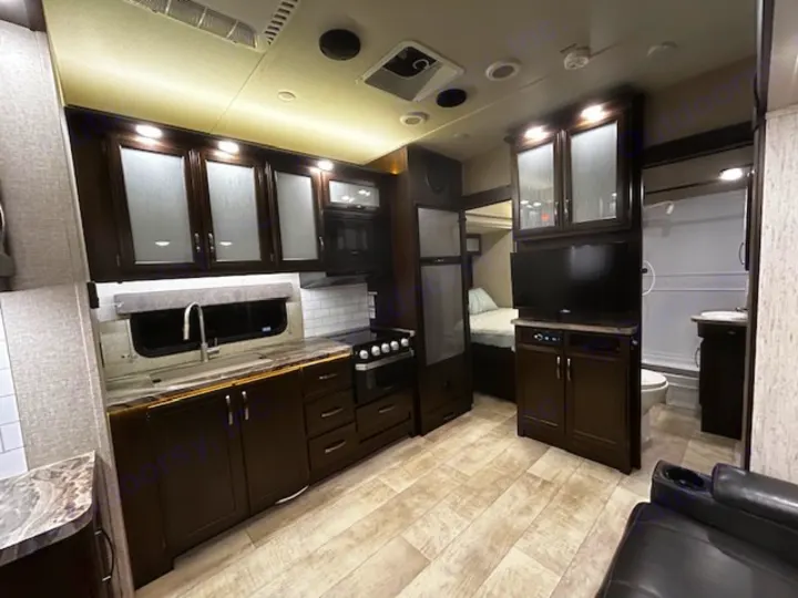 This RV rental offers a modern interior with a well-equipped kitchen, living area, and glimpse of the bedroom/bathroom.. Grand Design Momentum 2020