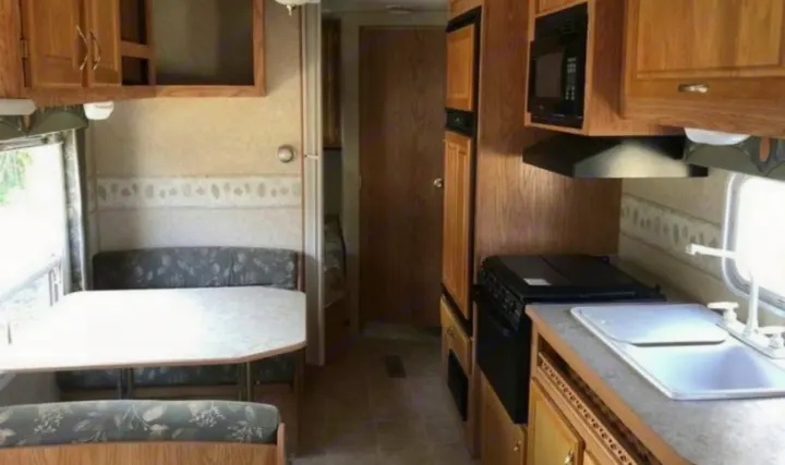 This rv rental features a well-equipped kitchen, a cozy dinette with bench seating, and a clear aisle, ready for your road trip.. Jayco Jay Flight 2005