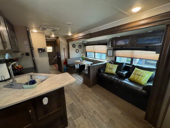 Spacious and modern RV rental interior featuring a kitchen, dining booth, and comfortable living area with a sofa.. Forest River Palomino Puma 2018