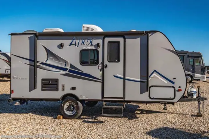 Side view of a sleek grey Apex travel trailer parked on a gravel lot, perfect for your rv rental outdoor adventure.. Coachmen Apex Nano 2018