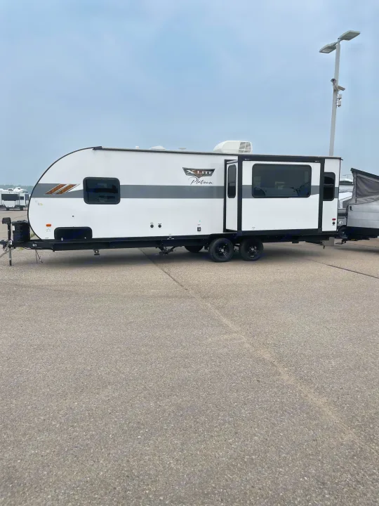 This white X-Lite Platinum travel trailer is an excellent RV rental option, parked on asphalt and ready for your next journey.. Forest River Wildwood X-Lite 2023