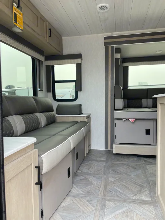 Modern gray interior of an RV rental, featuring comfortable seating, ample windows, and light wood cabinetry.. Forest River Wildwood X-Lite 2023
