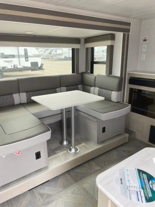 Interior view of a modern RV dinette with a U-shaped bench and table, ideal for an rv rental.. Forest River Wildwood X-Lite 2023
