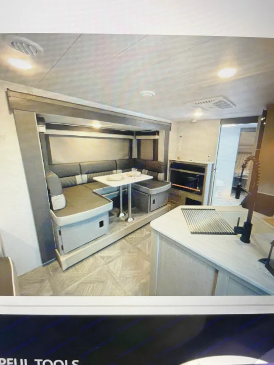 Cozy RV rental interior: Features a large U-shaped dinette, modern kitchen with sink, and bright lighting.. Forest River Wildwood X-Lite 2023