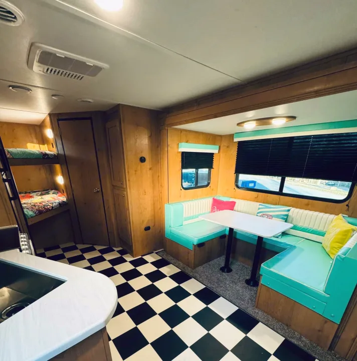 Charming RV rental interior with vibrant dinette, cozy bunk beds, and classic checkerboard floor.. Riverside RV Retro 2023