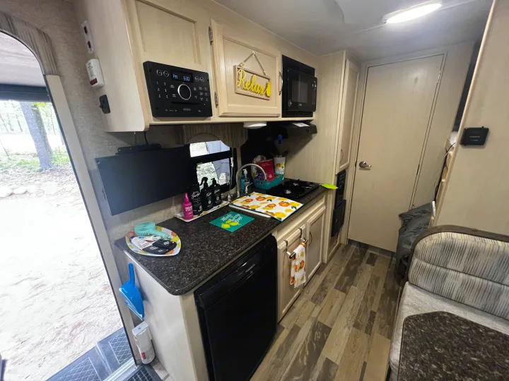 Cozy RV rental interior featuring a full kitchen with microwave, fridge, and sink, plus a comfy dinette for your travels.. Minnie Micro Minnie 2018