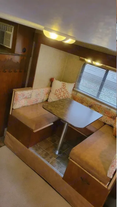 Bright RV rental interior showing a cozy dinette with U-shaped seating, central table, and window with blinds.. Spree Escape 2016
