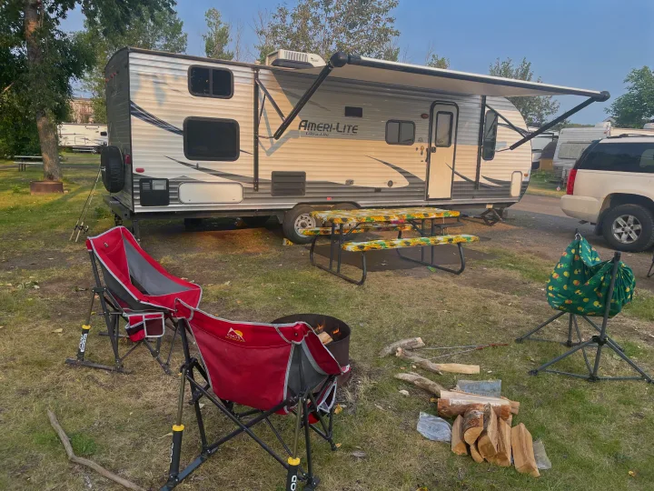 Enjoying an RV rental campsite: travel trailer, campfire, picnic table, and comfy chairs under an extended awning.. Gulf Stream Ameri-Lite 2016