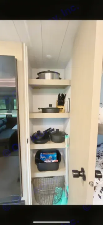 Organized RV rental kitchen storage. Shelves hold a slow cooker, pots, pans, knives, and cleaning supplies.. Forest River Salem Cruise Lite 2024