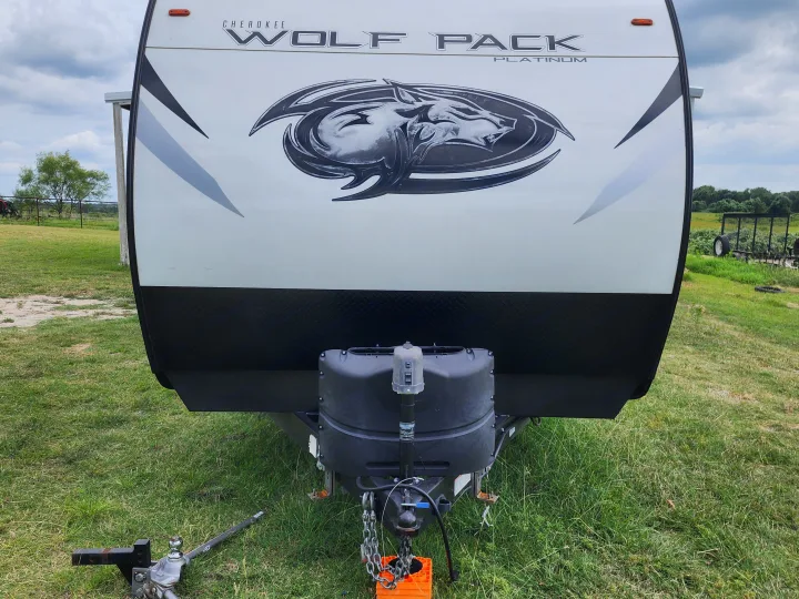 Front view of a white Cherokee Wolf Pack Platinum RV rental, ready for adventure in a grassy outdoor setting.. Forest River Wolf Pack 2023
