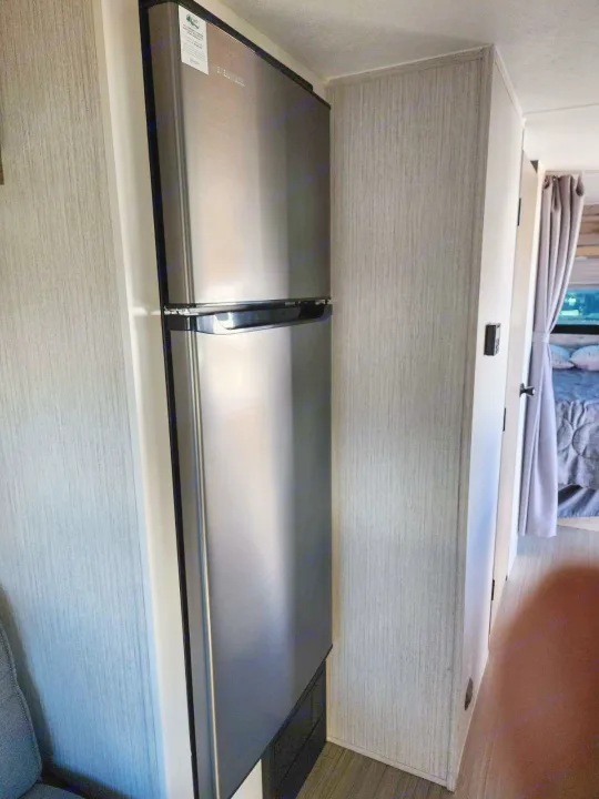 This RV rental boasts a modern stainless steel refrigerator built into the clean interior, leading to a comfortable bedroom.. Palomino Puma 2022