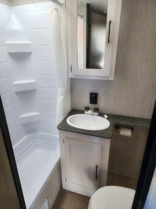Clean RV rental bathroom features a compact tub/shower, vanity with sink, and toilet, maximizing space for travelers.. Palomino Puma 2022