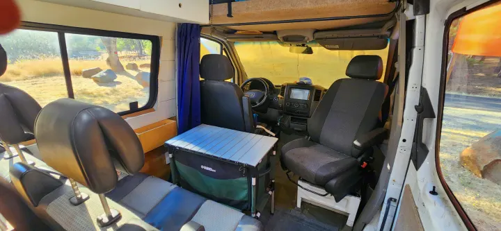 RV rental interior features front and rear seating, a portable dining table, and a scenic view through the side window.. Mercedes-Benz Sprinter 2011