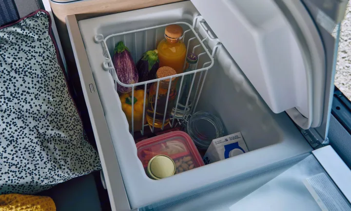 An open compact refrigerator inside an RV rental, stocked with healthy food and drinks.. Volkswagen California T6.1 4MO 2024