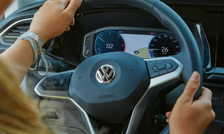 Driver's view in a modern car: hands on VW steering wheel, digital dashboard shows 26 km/h. Great for any rv rental trip.. Volkswagen California T6.1 4MO 2024