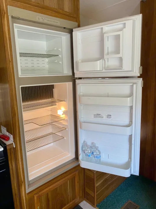 Clean, empty RV rental refrigerator and freezer, ready for your trip. Includes water bottles on the door shelf.. Forest River Cherokee Lite 2000