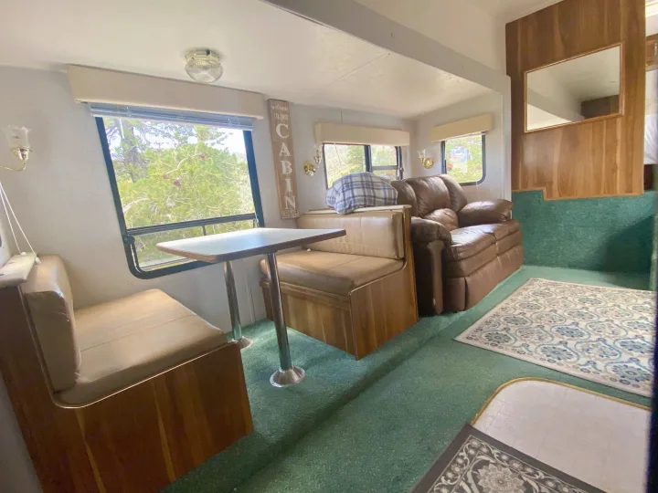 Step inside this inviting RV rental: a spacious living area featuring a dinette, lounge seating, and nature views.. Forest River Cherokee Lite 2000