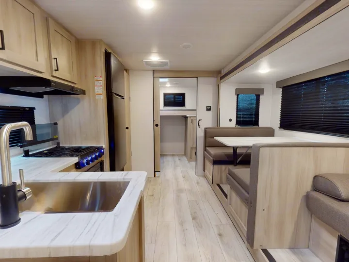 Spacious RV rental interior with a modern kitchen, dinette booth, and bunk beds, offering comfort for travel.. East to West Silver Lake 3250QB 2025