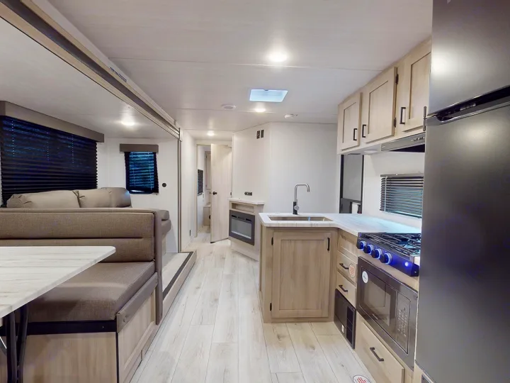 RV rental: Bright, modern interior featuring a well-equipped kitchen, dining booth, and sofa.. East to West Silver Lake 3250QB 2025