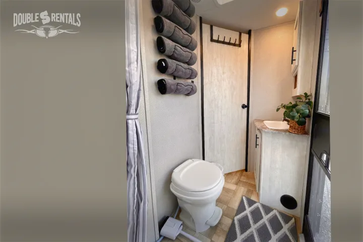 RV rental bathroom features a toilet, sink, stylish decor, and clever towel storage.. Shasta 26DB 2022