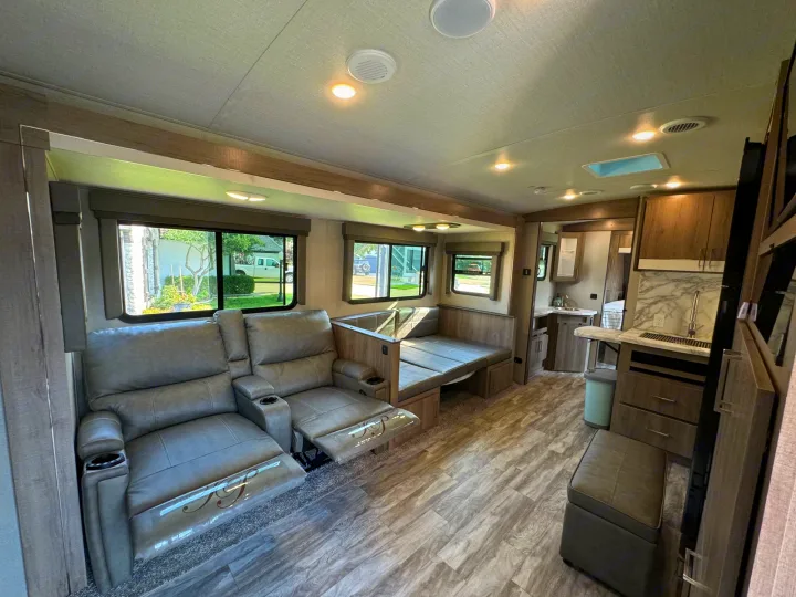 Spacious RV rental interior with recliners, dinette, and kitchen. Perfect for travel and camping adventures.. Grand Design Imagine 2022