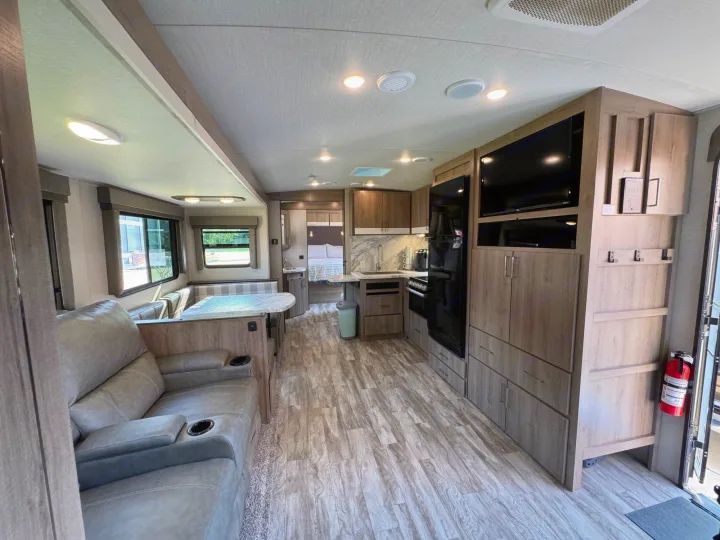 Comfortable RV rental interior with modern living space, full kitchen, and private bedroom area.. Grand Design Imagine 2022