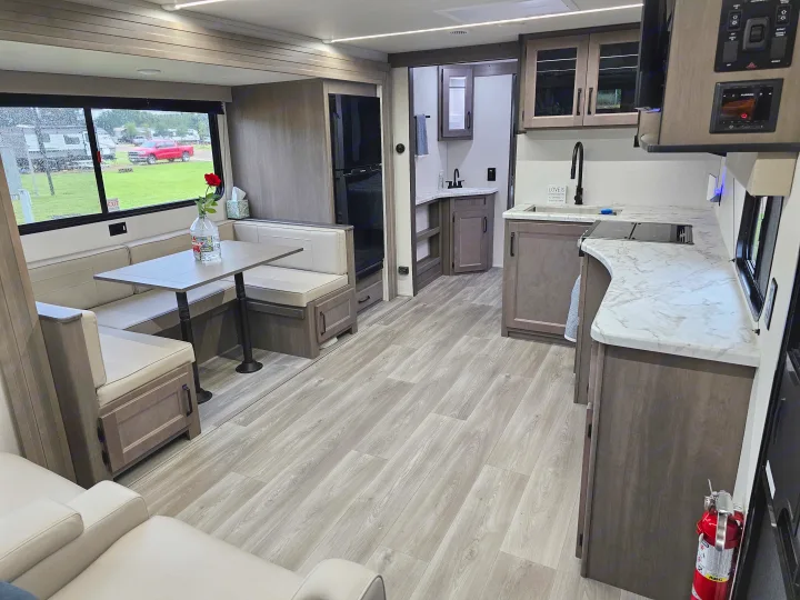 Bright rv rental interior featuring a modern kitchen, dinette, and light-colored furnishings, with wood-look flooring.. Grand Design Transcend Xplor 2024