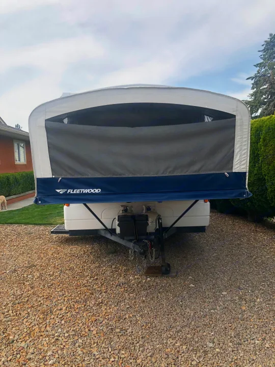 Front view of a Fleetwood pop-up camper RV, extended and parked on a gravel driveway. Consider this rv rental!. Fleetwood santa fe 2008