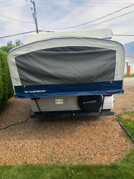 Pop-up RV rental: A Fleetwood camper partially set up with its canvas extension, parked on gravel. Great for travel.. Fleetwood santa fe 2008