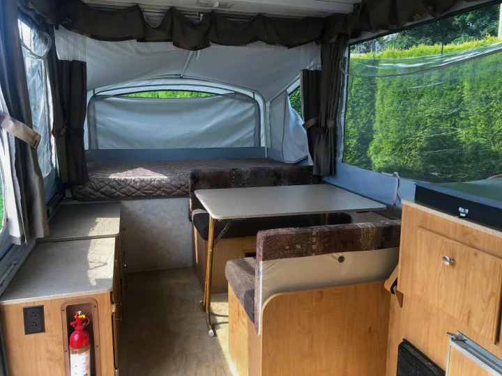Spacious pop-up camper interior for your RV rental, featuring a cozy bed, dinette, and bright views. Perfect for adventures.. Fleetwood santa fe 2008