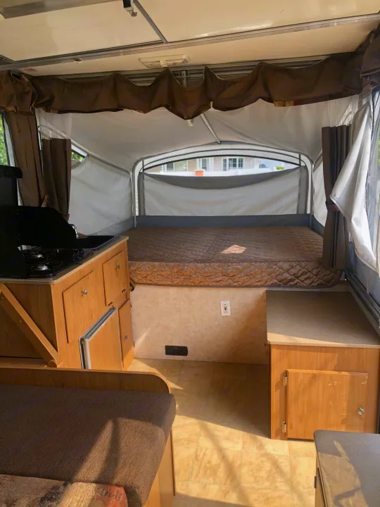 Pop-up RV rental interior: bed, compact kitchen with stove/sink, and seating. Plan your adventure!. Fleetwood santa fe 2008