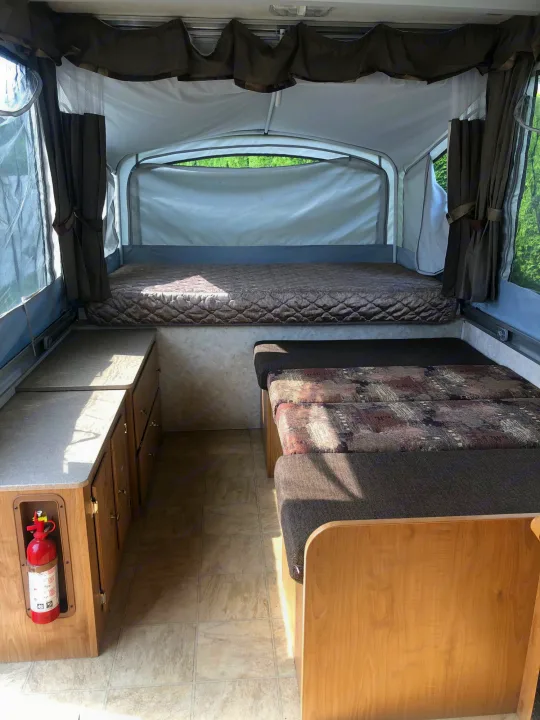 Inside an RV rental pop-up camper: a bed, convertible dinette, storage, and fire extinguisher, offering comfortable camping.. Fleetwood santa fe 2008