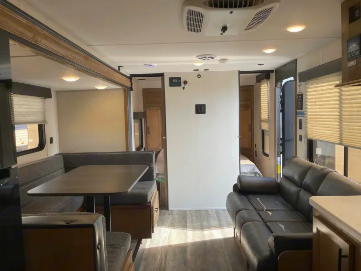 Spacious RV rental living area features a dinette, comfortable sofa, and kitchen amenities. Bright interior with wood-look flooring.. Forest River Cherokee Wolf Pup 2023