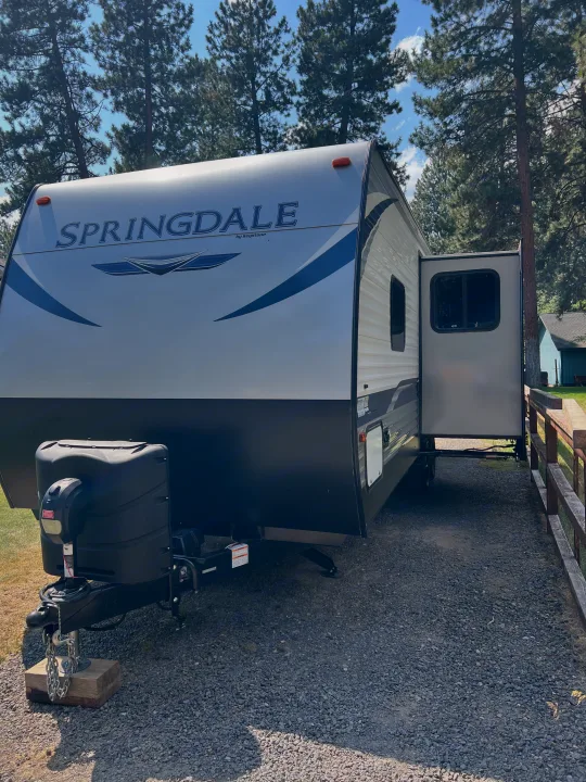 Spacious Springdale travel trailer, an ideal rv rental. Parked on a gravel site with slide-out extended for camping.. Keystone RV Springdale 2021